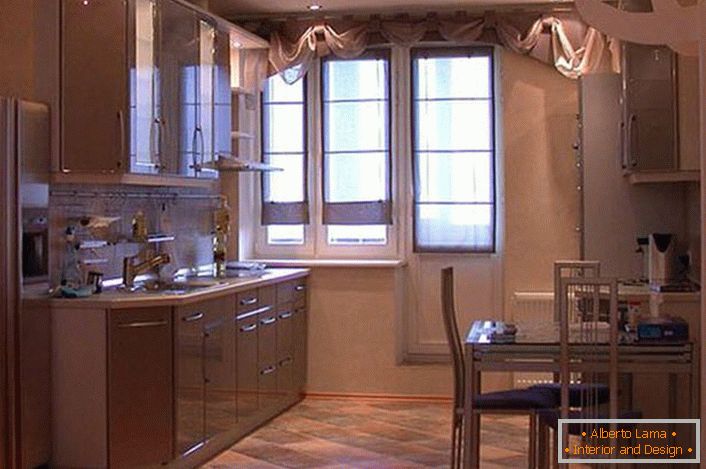 Uma cozinha espaçosa com armários suspensos em tons de bege claro parece atraente e requintada. Em vez de uma despensa, o designer fez um nicho, onde por conveniência foi colocada uma geladeira.
