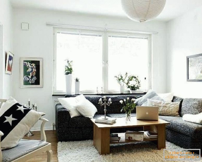 Uma pequena sala de estar em branco com um sofá de canto escuro e uma janela