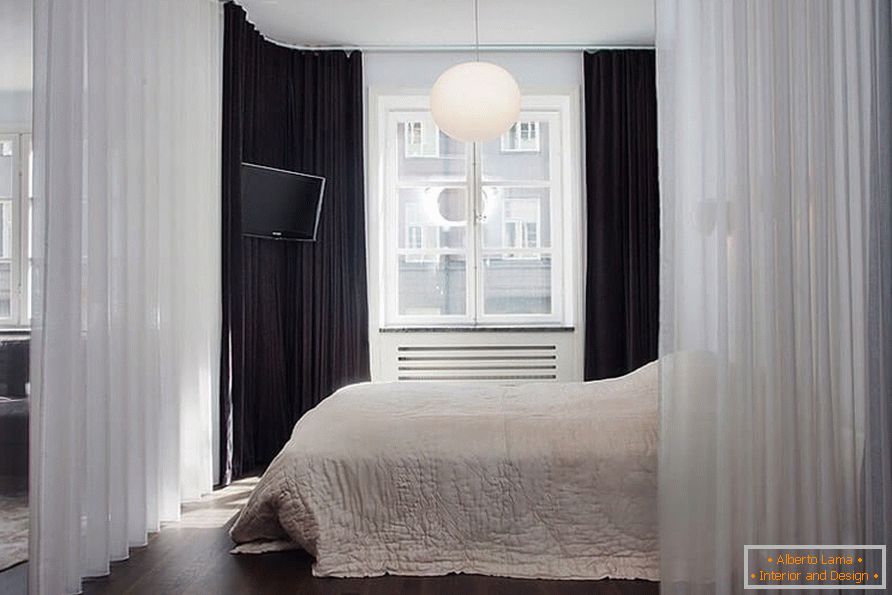 Uma cama com uma cortina em um apartamento de um quarto de 36 metros quadrados