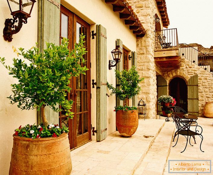 O pátio в средиземноморском стиле украшают горшки с живыми растениями. Привлекательный дизайн, мебель с витиеватыми спинками, керамические горшки создают уютную, расслабляющую атмосферу. 