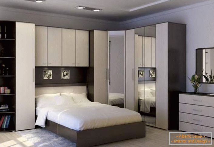 Parede de canto funcional para o quarto. O espaço corretamente projetado permanece espaçoso e não confuso. Um lugar para guardar permite armários com dobradiças acima da cama.