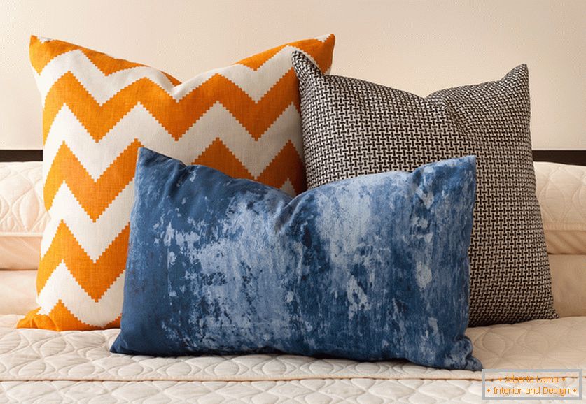 Almofadas decorativas laranja, azul e preto e branco brilhantes com estampas interessantes na cama
