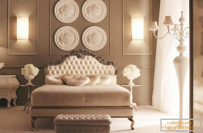 Na cabeceira da cama, a parede é decorada com uma composição de estuque de designer. Requintada decoração do quarto em estilo Art Deco.