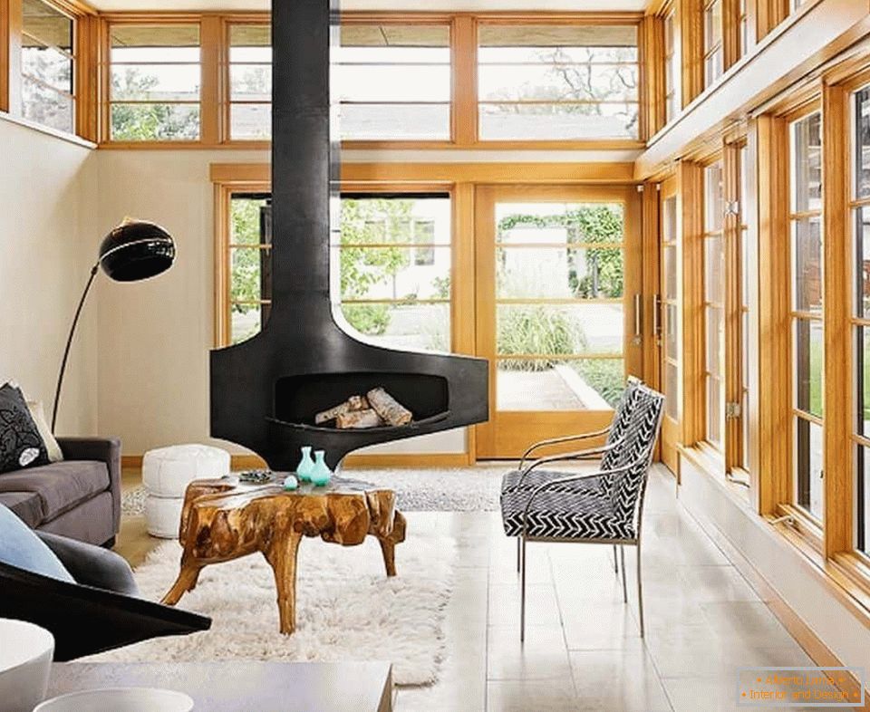 O design da sala de estar na casa com lareira e janelas panorâmicas