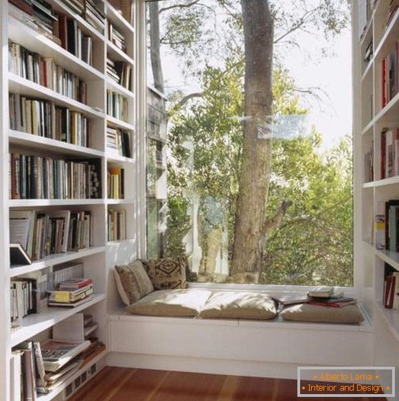 Sentado no peitoril da janela e estantes de livros perto da janela