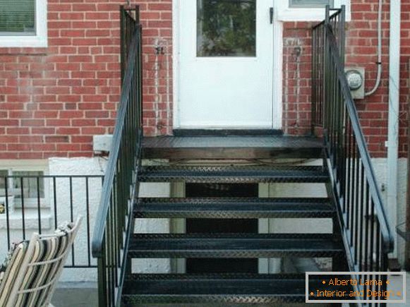 Uma pequena varanda de metal com uma escada para a casa de tijolos