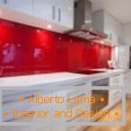 Móveis brancos e um avental vermelho no interior da cozinha