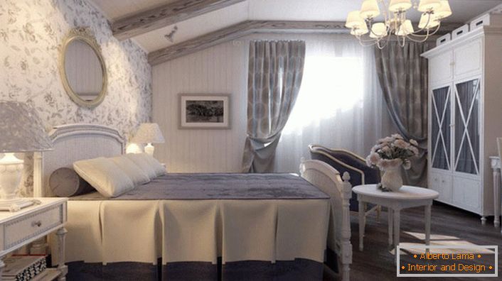 O quarto no estilo country é feito em tons azuis suaves. A parede na cabeceira da cama é coberta com papel de parede com um padrão floral.