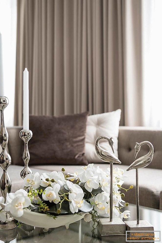 Composição de orquídeas, velas e outros elementos decorativos em cima da mesa na sala de estar
