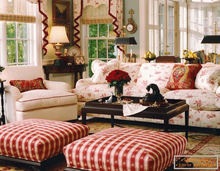 Uma sala de estar simples, modesta e aconchegante em estilo inglês em uma pequena casa de campo. Os toques de vermelho tornam a atmosfera da sala relaxada e alegre.