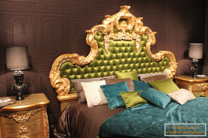 Um alto encosto ornamentado na cabeceira da cama é coberto de seda verde-oliva. Almofadas interessantes de cores e colchas contrastantes na cama.