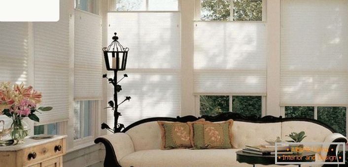 Cortinas plissadas de ar de cor única moderna não sobrecarregam a atmosfera refinada da sala de estar de uma antiga casa de campo. 