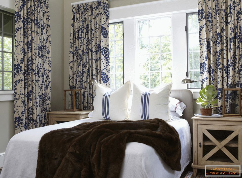 Flores azuis nas cortinas e listras nos travesseiros são harmoniosamente combinados no interior do quarto
