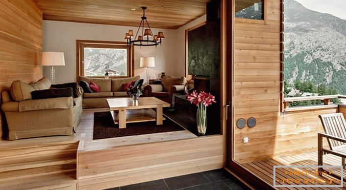 O sótão da casa com acesso à varanda é decorado no estilo de um chalé. A cor da madeira clara parece rentável em combinação com um piso marrom escuro.