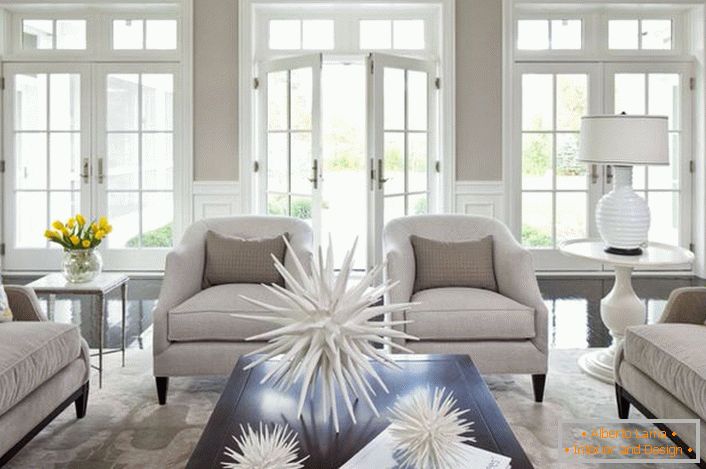 A sala de estar em uma casa grande em estilo country americano é notável por seus móveis maciços e janelas panorâmicas. Flores amarelas na mesa e padrão em tom nas almofadas se tornaram o principal destaque do conceito. 