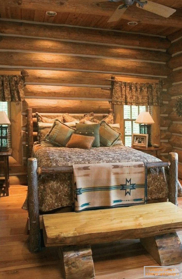 Um exemplo clássico de um quarto em estilo rústico. Interessante cama de uma casa de toras áspera, não tratada. 
