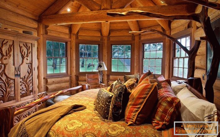 Um dos quartos da casa perto do lago é feito no estilo do país rural. Decoração de madeira. Móveis maciços e elementos de decoração são selecionados nas melhores tradições de estilo.
