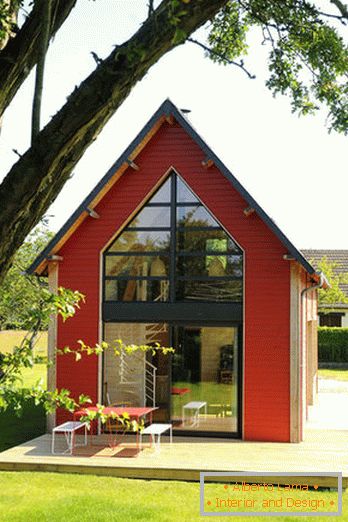 Interior de uma pequena casa de madeira com grandes janelas