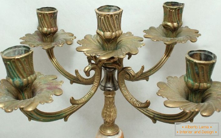 Um elegante candelabro feito de latão com motivos florais harmoniosamente é escrito no interior no estilo do país.
