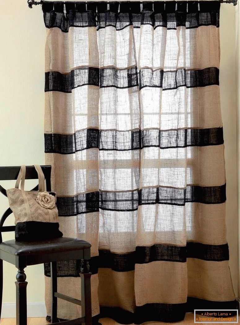 Uma cadeira pela janela com cortinas de pano de saco