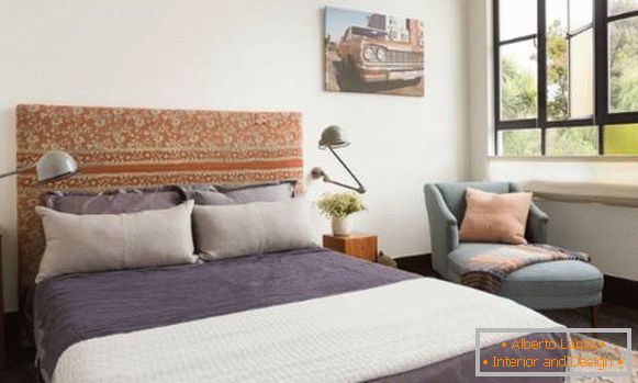 Uma cama feita à mão com uma cabeceira macia - foto no interior
