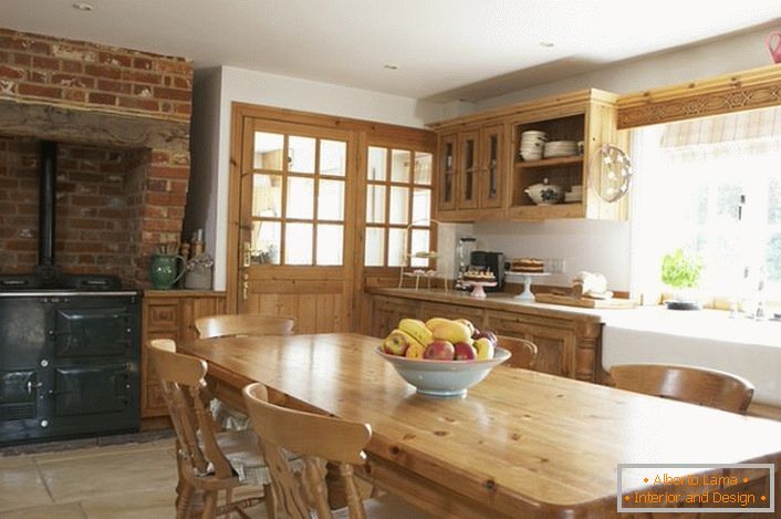 Cozinha espaçosa em estilo country. Móveis de madeira e decoração de tijolos sobre o fogão dão um estilo natural e romântico.