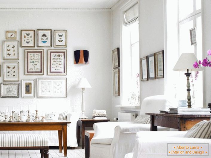 A acolhedora sala de estar em estilo escandinavo é feita em branco. É interessante decorar a parede com molduras de diferentes tamanhos.