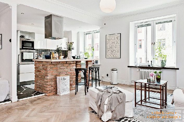 O apartamento estúdio é decorado em estilo escandinavo. A cozinha é separada da sala por um balcão de bar feito de tijolos.