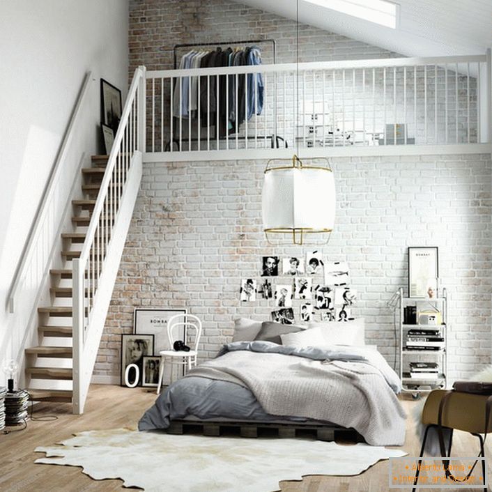 O quarto em estilo escandinavo é funcionalmente dividido em duas zonas. Uma escada de madeira leva ao segundo andar, onde há um pequeno vestiário na cama.