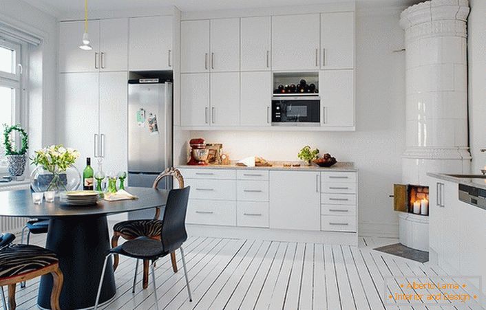 Lareira de azulejos, feita com azulejos de cerâmica branca, se encaixa organicamente no interior da cozinha em estilo escandinavo.
