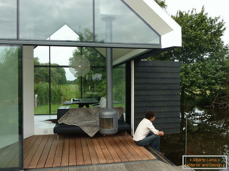 Terraço de uma pequena casa de vidro à beira do lago na Holanda
