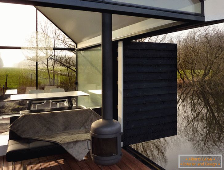 Terraço de uma pequena casa de vidro à beira do lago na Holanda