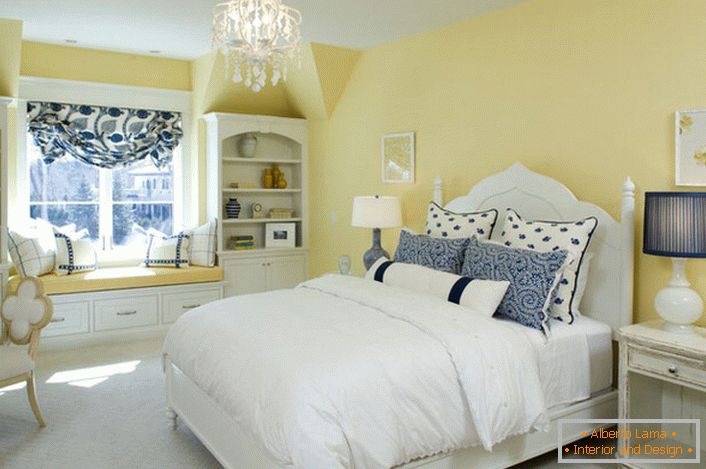 A cor amarela desbotada do acabamento se harmoniza com os elementos branco e azul da decoração. Uma combinação incomum é uma solução ousada para um quarto em estilo campestre.
