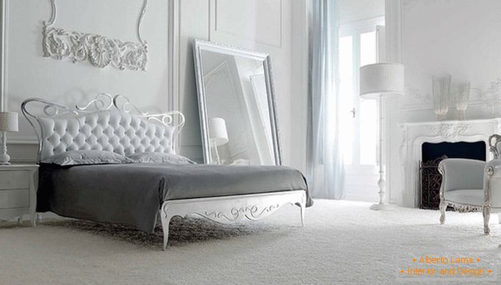A parede na cabeceira da cama é decorada com moldagem decorativa de estuque. O interior branco é notável por seu enorme espelho grande em um quadro simples e lacônico.