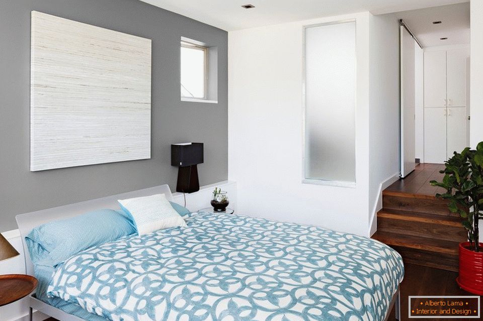 Roupa de cama azul e paredes cinzentas no quarto