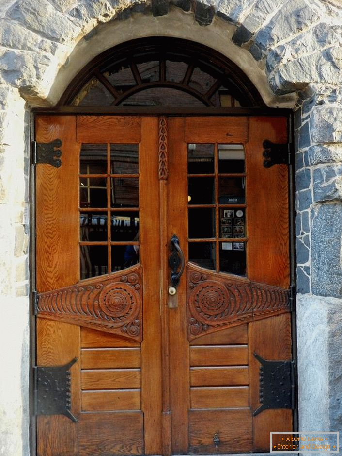 Portas em estilo Art Nouveau decoram a porta da frente de uma casa de campo com uma fachada de pedra natural. 
