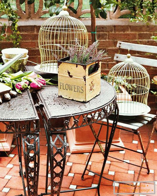 Mesa forjada, caixas com flores e gaiolas para pássaros