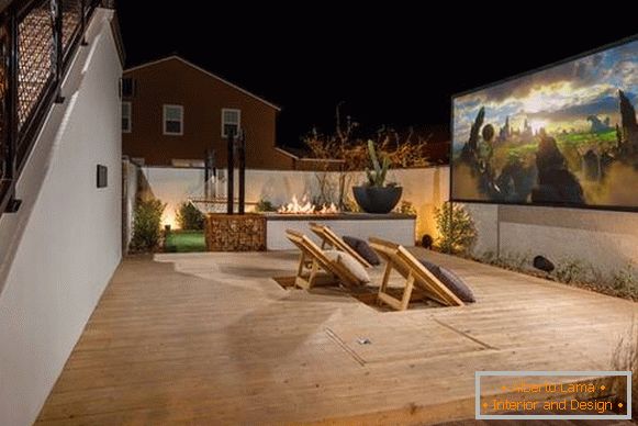 Um terraço ao ar livre ligado à casa - uma foto com um projetor