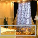 Uma foto, uma luminária de pé e uma cortina com o mesmo padrão